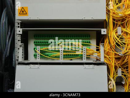 Pannello ravvicinato all'interno di un contenitore di distribuzione wifi, sono presenti molte prese e prese jack, inoltre è dotato di un cartello di radiazione laser Foto Stock