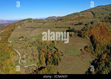 Vista aerea della strada sterrata del villaggio sulle montagne. Foresta autunnale e prato di campagna in droni Foto Stock