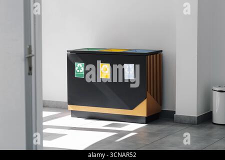 Contenitori di riciclaggio nel corridoio interno. Separazione dei rifiuti e stile di vita ecologico. Design moderno dei contenitori per rifiuti per un ambiente pulito. Foto Stock