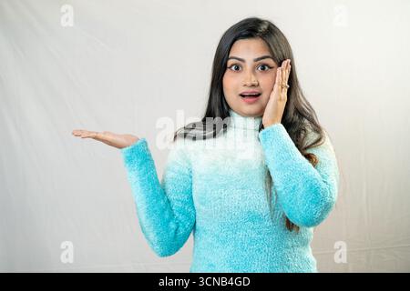 Una giovane donna con un'espressione sorpresa e un gesto di palma aperto. Foto Stock