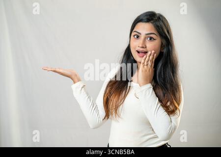 Una giovane donna con un'espressione sorpresa e palme aperte. Foto Stock