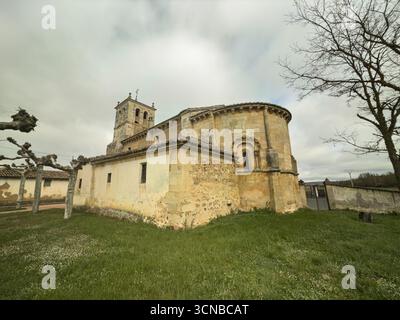 Storica chiesa romanica con abside e torre, circondata da erba e alberi Foto Stock