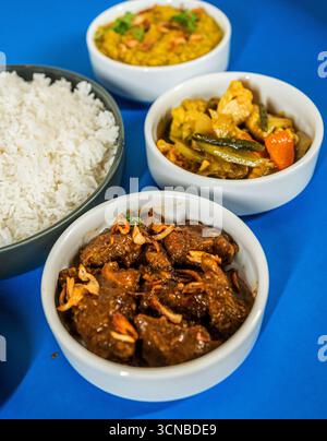Un primo piano ad angolo alto di un piatto di cibo asiatico, con una porzione di riso fritto, una frittura in padella con carne e verdure e cetrioli a fette. Foto Stock