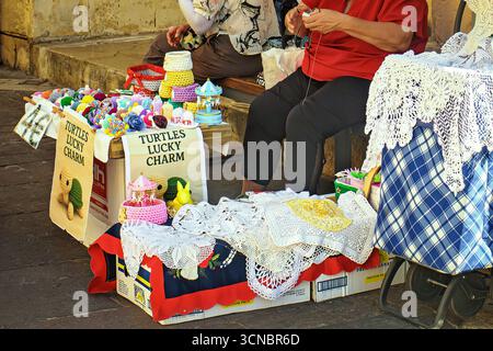 La Valletta, Malta - 09.17.2025: Souvenir fatti a mano all'uncinetto: Pizzi, doilies e tartarughe giocattolo in una bancarella del mercato di strada. Foto Stock