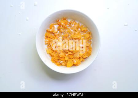 Fiocchi di mais in un recipiente su sfondo bianco. Scorte alimentari Foto Stock