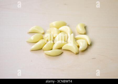 Spicchi d'aglio freschi e crudi isolati su fondo di legno. Il suo nome scientifico è Allium sativum. Localmente in Bangladesh, si chiama Rosun. Foto Stock