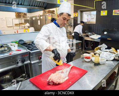 BAKU, AZERBAIGIAN-24 MAY2019 : lo chef prepara anche piatti con gambo di agnello. Il processo di cottura dello chef maschio dello stinco di agnello in una cucina professionale. Cucinare Foto Stock