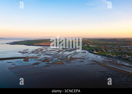 Vista aerea di Skerries Beach con la bassa marea con tramonto dorato, campi verdi e quartiere costiero con la luce serale Foto Stock