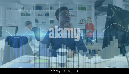 Analista dei dati che indossa una camicia blu che esamina i grafici del desktop sui monitor in un ufficio open space Foto Stock