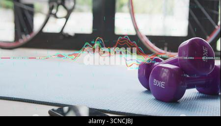 Manubri viola da 3 kg appoggiati su un tappetino blu nella palestra di casa, con smartphone, ruota della bicicletta, porte in vetro Foto Stock