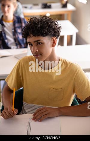 Diversi compagni di classe adolescenti che scrivono su quaderni con matite Foto Stock