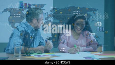 Revisione dei campioni di colore colleghi che indossano camicie che evidenziano la carta in ufficio, con sovrapposizione delle mappe Foto Stock