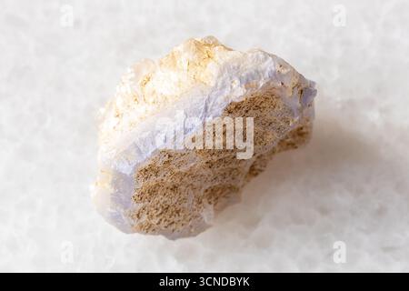 Assaggio di minerale di agata blu ruvida su sfondo di marmo bianco da vicino dall'Uzbekistan Foto Stock