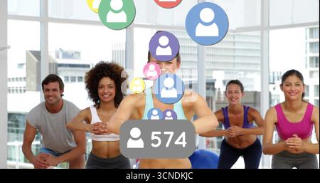 Lezione di guida per istruttori femminili all'avanguardia attraverso gli squat nella sala fitness, con icone utente fluttuanti Foto Stock