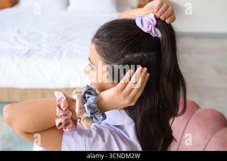 Bella donna con coda di cavallo e scrunchies in camera da letto, primo piano Foto Stock
