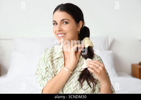 Bella donna che fa la coda di cavallo con le scrunchies in camera da letto Foto Stock