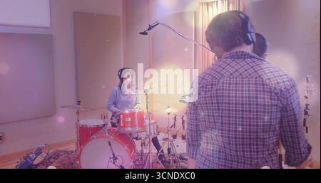 Due musicisti che indossano le cuffie che suonano la batteria rossa e cantano in studio con il microfono Foto Stock