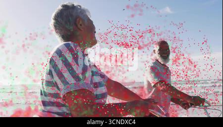 Una coppia senior che pedala indossando una camicia a righe e una polo su una pista ciclabile sul mare, con biciclette Foto Stock