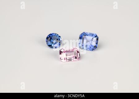 Tre gemme colorate diverse vengono visualizzate su uno sfondo bianco. La gemma blu è la più grande e la gemma rosa la più piccola. La gemma rosa è nel Foto Stock