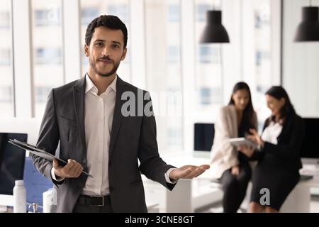 Giovane uomo professionale positivo del Medio Oriente che detiene uno spazio di copia Foto Stock