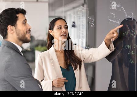 Coppia diversificata di colleghi motivati e impegnati che discutono dello schema del flusso di lavoro Foto Stock