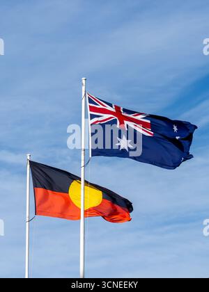 Bandiera nazionale australiana e bandiera degli aborigeni australiani che sventolano con il cielo blu sullo sfondo Foto Stock
