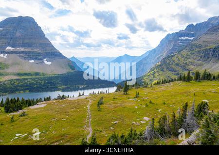 Una vista panoramica cattura il tranquillo lago nascosto e la catena montuosa circostante all'interno del Glacier National Park Foto Stock