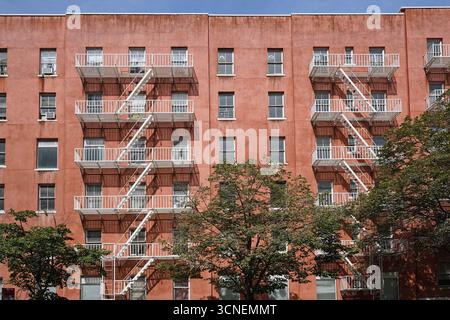 Edificio di appartamenti in stucco rosa a New York con scale antincendio esterne Foto Stock