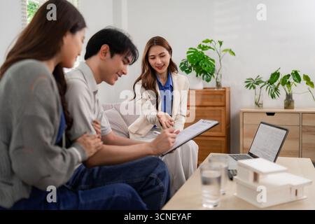 Agente immobiliare professionale che fornisce consulenza alle coppie asiatiche a casa discutono di investimenti immobiliari futuri processi decisionali informati in materia di alloggi Foto Stock