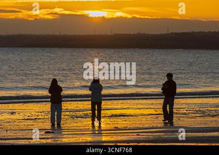 Portobello, Edimburgo, Scozia, Regno Unito. 21 settembre 2025. Alba fredda a 6 gradi centigradi dal Firth of Forth. Nella foto: I turisti asiatici osservano il sorgere del sole e scattano fotografie accanto al Firth of Forth. Credito: Arch White/alamy notizie dal vivo. Foto Stock