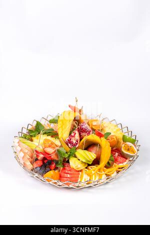 Piatto di frutta vivace con ananas, mango, pompelmo e menta. Presentazione elegante su uno sfondo bianco pulito. Foto Stock
