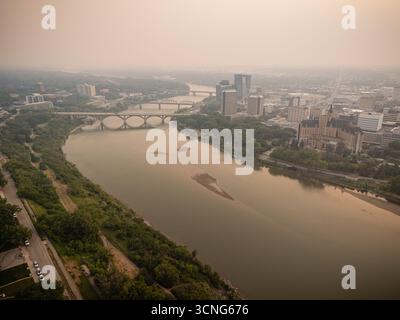 Vista aerea del centro di Saskatoon, Saskatchewan, con fumo di fuoco che incanta lo skyline e la valle del fiume. Foto Stock