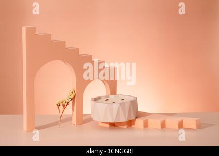 Una scena minimalista con una candela bianca in un supporto geometrico, un morbido sfondo pesca e strutture astratte simili a scale. L'atmosfera trasmette Foto Stock