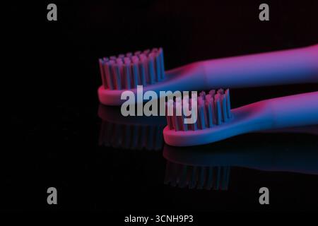 Testina dello spazzolino con gradiente rosso blu chiaro al neon su sfondo scuro Foto Stock