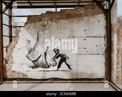 Borodyanka, Ucraina 1 maggio 2024 il murale di Judo di Banksy su un muro danneggiato. Un'immagine suggestiva del murale Banksy su un muro sbriciolato, un bambino che lancia un adulto Foto Stock