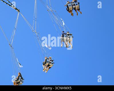 Monaco, Germania. 21 settembre 2025. I visitatori potranno godersi l'alto swing sotto un cielo azzurro all'Oktoberfest di Monaco, Baviera, Germania, il 21 settembre 2025. La famosa attrazione solleva i partecipanti sopra i terreni del festival. (Foto di Michael Nguyen/NurPhoto) credito: NurPhoto SRL/Alamy Live News Foto Stock