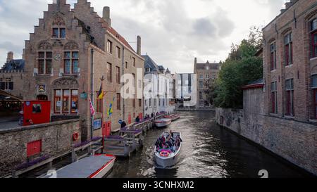BRUGES, BELGIO - 15 SETTEMBRE 2025 - crociera turistica in barca lungo un pittoresco canale con edifici medievali in mattoni che costeggiano l'acqua Foto Stock