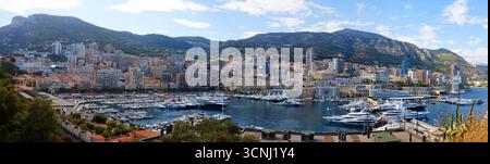 Vista sopraelevata del paesaggio urbano di Monaco con tetti rossi, grattacieli a strati e lussureggianti colline verdi. Paesaggio urbano panoramico del Principato, che si fonde Foto Stock