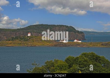 Una vista panoramica del faro di Fort Point che sorge su una piccola collina vicino al villaggio costiero di Trinity, Terranova. Circonda scogliere rocciose A. Foto Stock