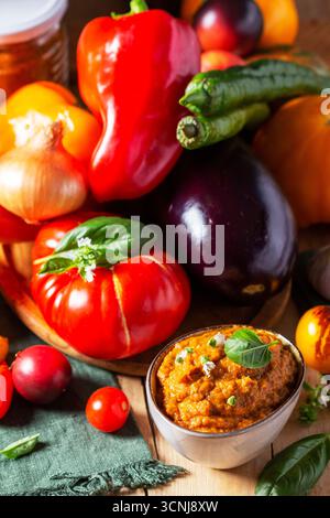 Caviale di melanzane in vaso di vetro e verdure su fondo di legno. Foto Stock
