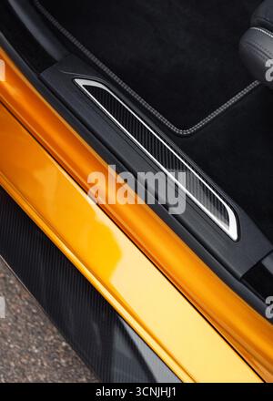 Soglia della portiera di cicatrice sportiva color ambra. Vista dell'auto parcheggiata che mostra l'ampia soglia della portiera con piastra decorativa in fibra di carbonio. Foto Stock