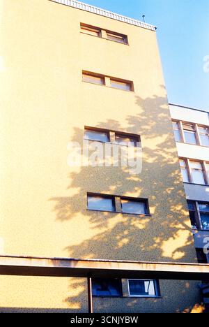Fotografia analogica di un muro di un edificio in piastrelle di mosaico giallo degli anni '1960, in contrasto con il cielo azzurro. Una tranquilla vista d'archivio della città di metà secolo Foto Stock