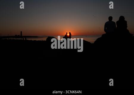 Un tramonto mozzafiato in Islanda, dove vivaci tonalità di arancione, rosa e viola illuminano il cielo a Gótta Seltjarnarnes Foto Stock