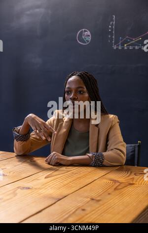 Donna d'affari afroamericana che gestiva e spiega in sala riunioni con lavagna Foto Stock