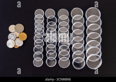 Monete con capsule di plastica vuote su sfondo nero Foto Stock