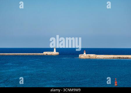 Vista panoramica dei fari maltesi e frangiflutti all'ingresso del Grand Harbour, del blu Mar Mediterraneo e dello skyline in una giornata di sole. Foto Stock
