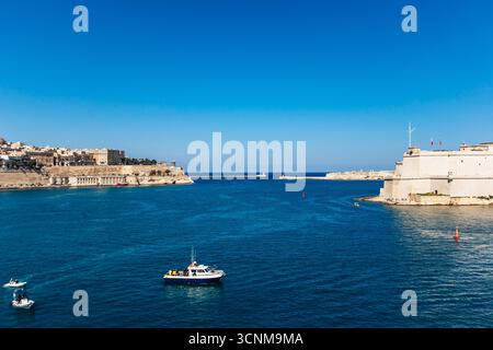 Vista panoramica dei fari maltesi e frangiflutti all'ingresso del Grand Harbour, del blu Mar Mediterraneo e dello skyline in una giornata di sole. Foto Stock