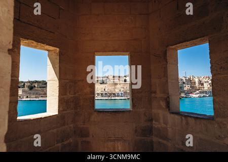 Vista panoramica sul Porto grande attraverso le finestre dello storico posto di guardia di Senglea, guardando verso Floriana e il lungomare di la Valletta e la fortifica Foto Stock