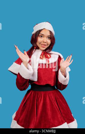 Donna in costume festoso di babbo natale sorridente su sfondo blu Foto Stock