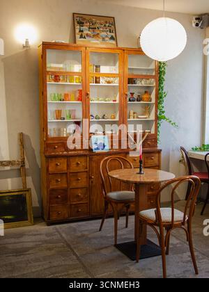Intimo interno da caffetteria con armadietto in legno vintage, sedie e luce calda e soffusa, concetto di stile urbano. Foto Stock